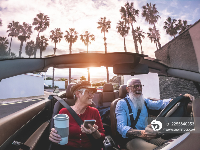 Senior trendy couple inside a convertible car on holiday time - Main focus on woman face