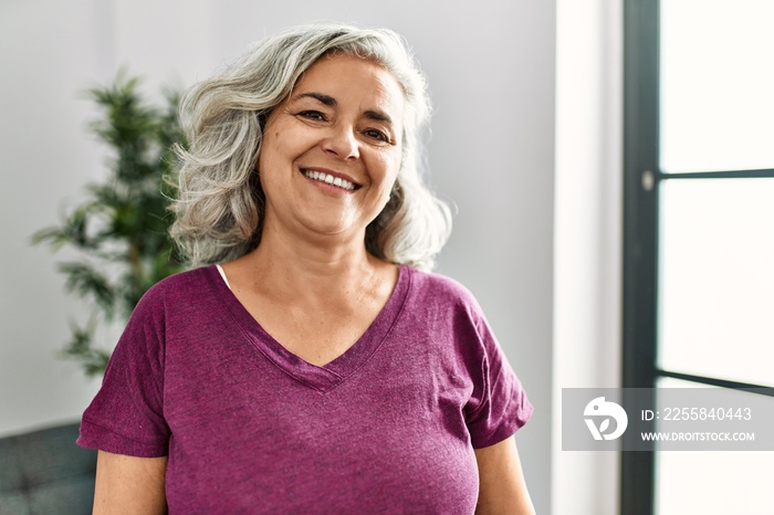 Middle age grey-haired woman smiling happy standing at home.