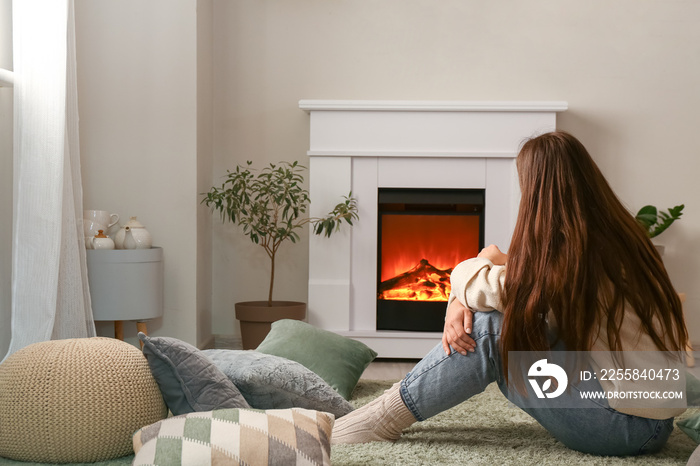 Woman sitting near fireplace at home