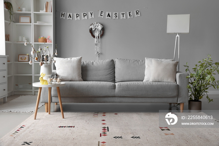 Interior of living room with sofa, tree branches and Easter eggs