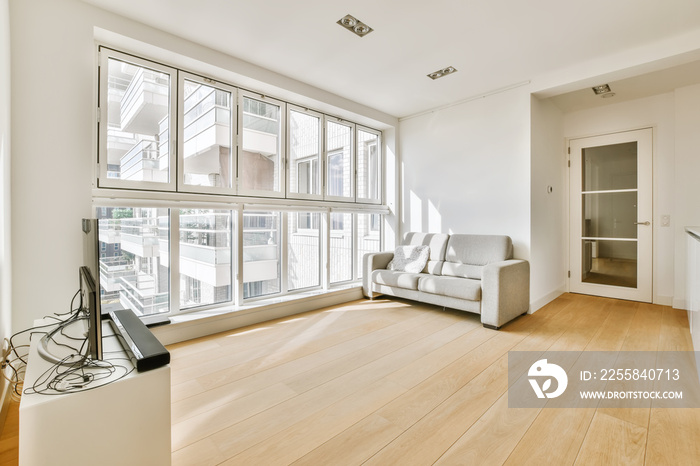 a living room with wood flooring and white walls, including a large window that looks out onto the s