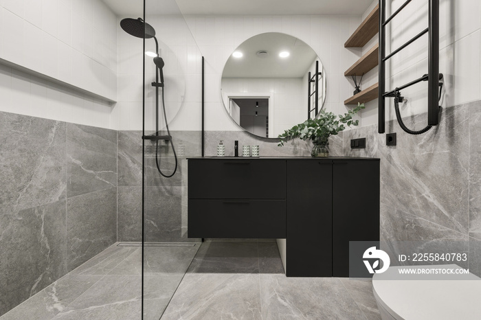 Modern minimalistic bathroom interior design with grey stone tiles, black furniture, eucalyptus in g