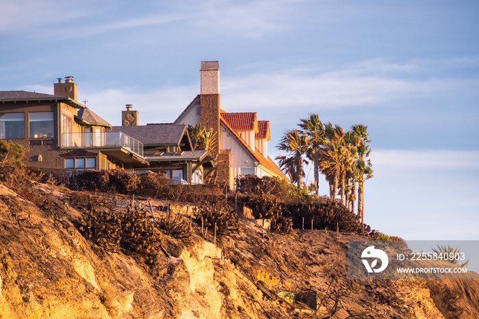 Sunset view of mansions built on top of cliffs on the Pacific Ocean coast, Malibu, Los Angeles count
