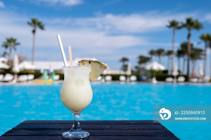 Pinacolada summer cocktail on the wooden table near the swimming pool, all inclusive resort