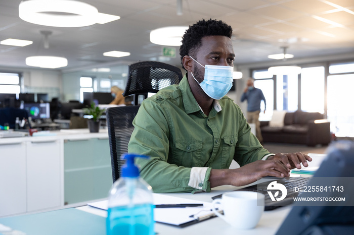 Businessman wearing face mask using computer at modern office