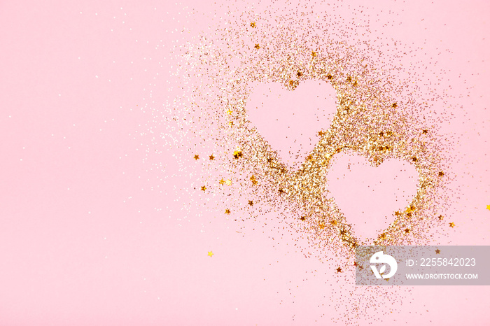 Two golden glitter hearts on a pink background