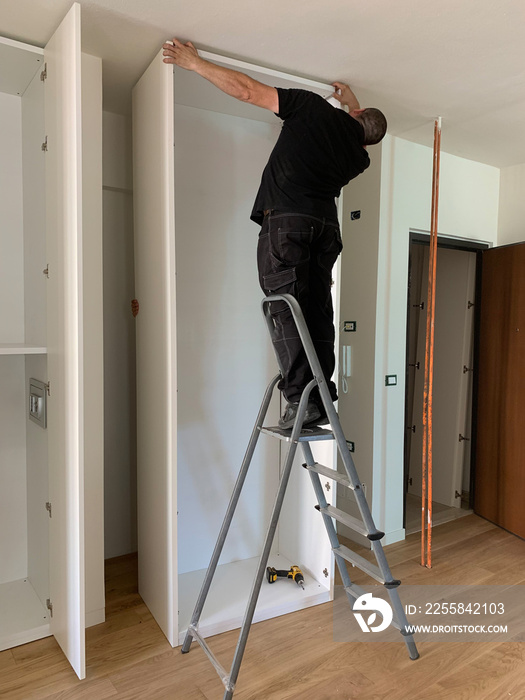 Carpenters installing closet cupboard doors in a white bedroom wardrobe, walk in closet. Partially i