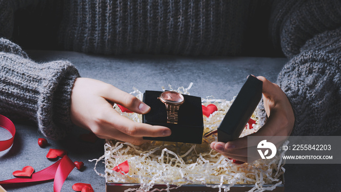 Female hands open a gift with a clock for Valentine Day