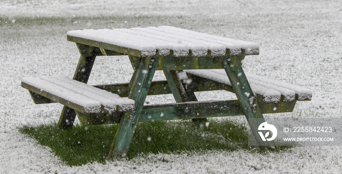 Picnic table under a fall of snow in a snowstorm