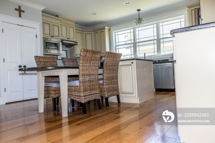 Low angle view of a cream colored new construction kitchen with black granite countertops and wood f