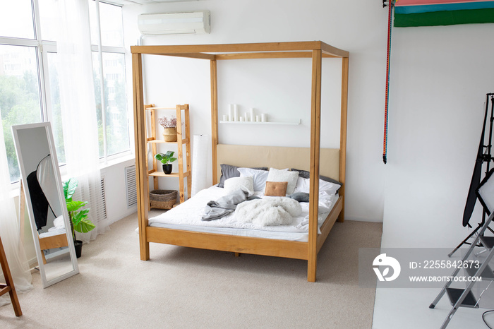a wooden double bed in a large white room. interior photo zone in a photo studio