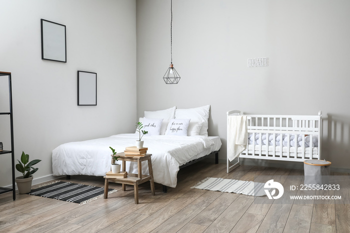 Interior of light bedroom with crib and blank frames