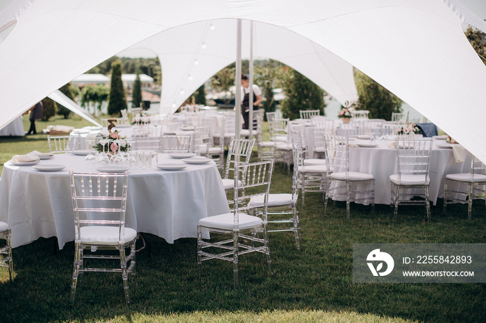 banquet table setting under a white tent on the grass