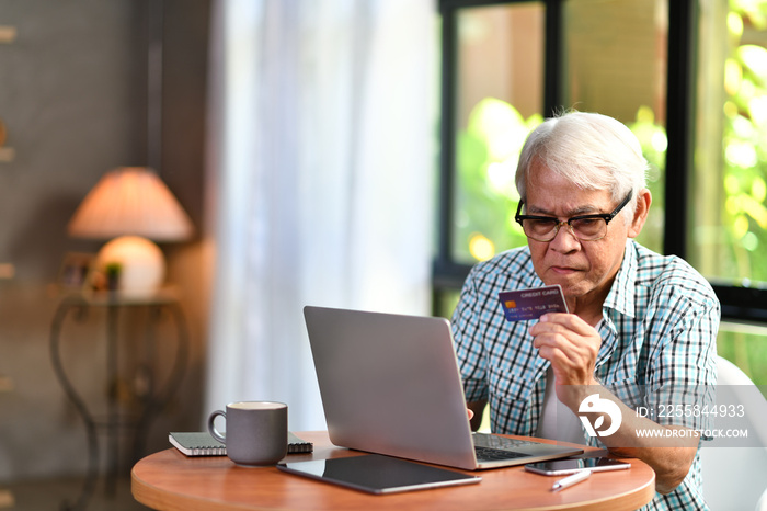 Asian senior man looking confuse when using credit card for online shopping