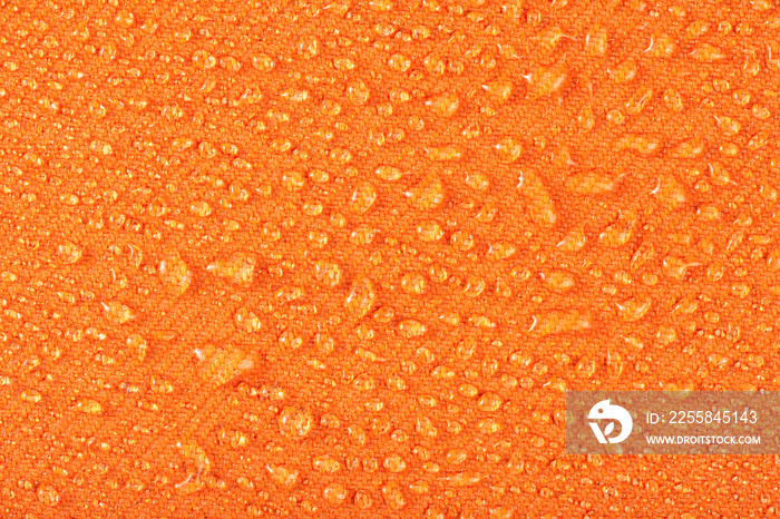 Waterproof clothing or upholstered furniture made from waterproof textiles. Drops of water on orange