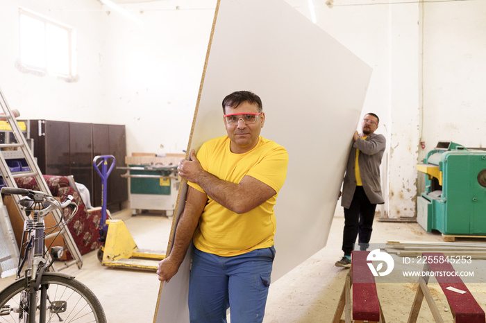 Carpenter apprentice carries materials in the carpentry workshop