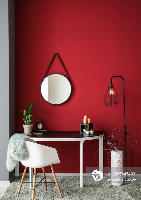 Interior of room with table and mirror on color wall