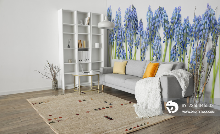 Stylish interior of modern living room with grey sofa and printed beautiful flowers on wall