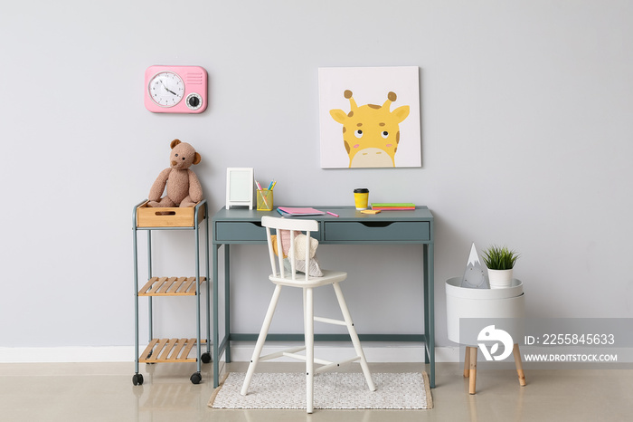 Stylish workplace with paper cup and toys in child room