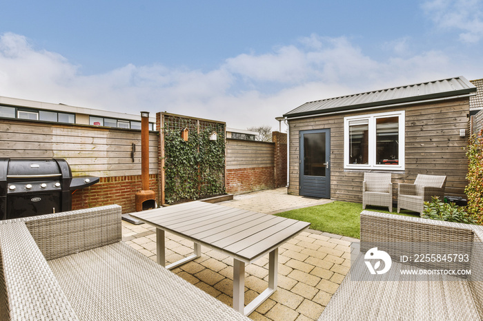 Neat paved patio with sitting area and small garden near wooden fence