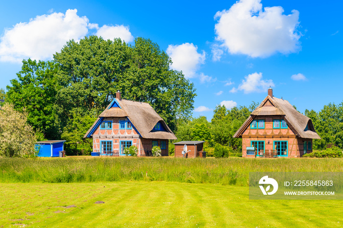 Traditional thatched roof house on green meadow in Gross Zicker village on sunny summer day, Ruegen 