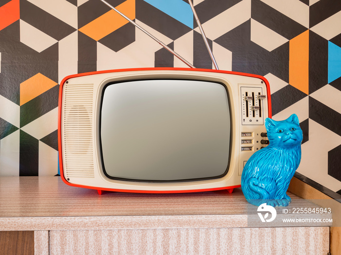 Retro television with vintage wallpaper in the background. Interior decoration ceramic figure from t