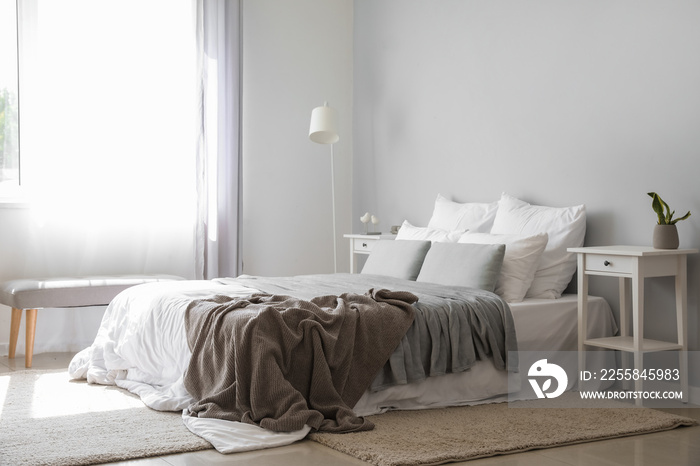 Interior of modern room with big bed, tables and lamp