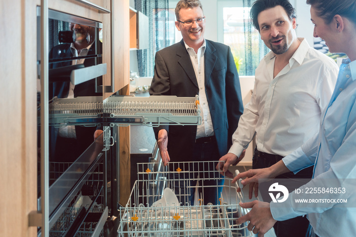 Couple checking dishwasher of new kitchen in the showroom