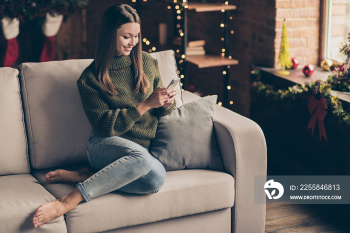 Full size photo of positive cheerful brown hair girl sit on divan use cellphone enjoy christmas vaca