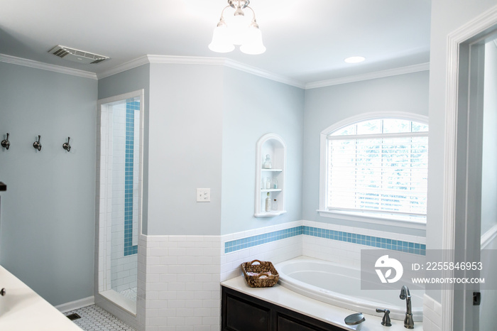 bathtub area of 1950s style bathroom with tile floor and dark brown cabinets in white and blue acce