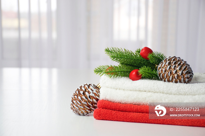 Stack of red and white towels with fir branches, red toys and pine cones with tulle window on backgr