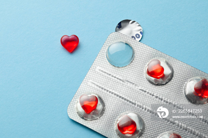 Love pills. Blister pack with red heart shaped pills. Tablets for lovers or potency. Blue background