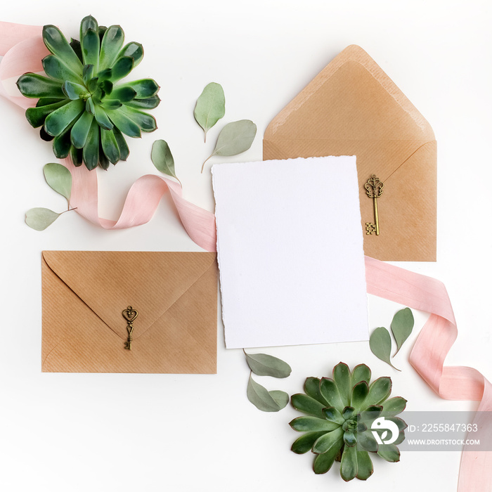 Flat lay shot of letter and eco paper envelope on white background. Wedding invitation cards or love