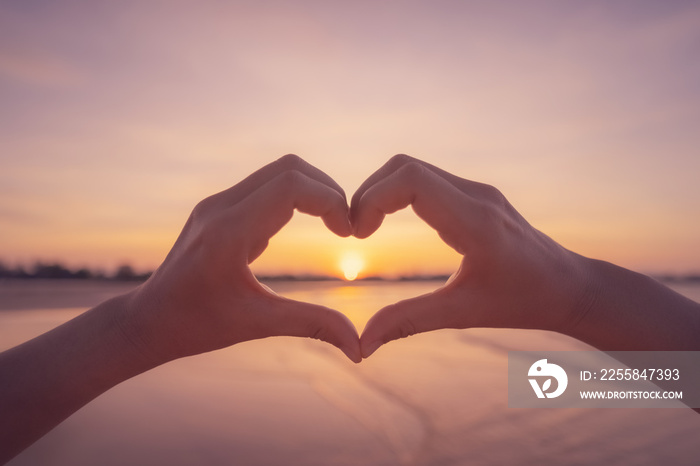 Female hands heart shape on sunset sky at tropical beach abstract background. Copy space of happy lo