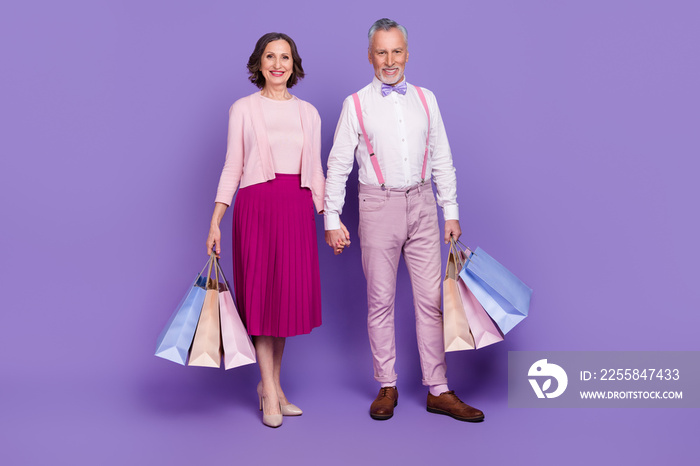 Full size photo of two lovely shopaholic hold arms packages isolated on violet color background