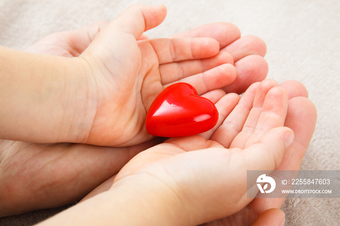 adult and child hands holding red heart