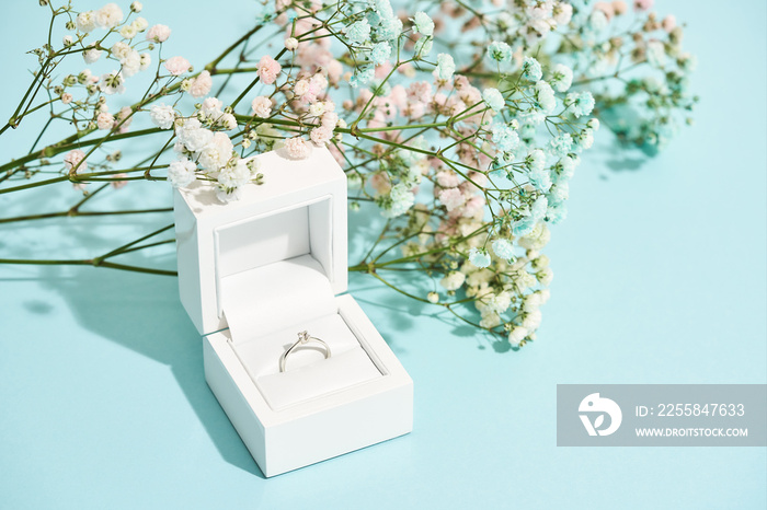 Romantic surprise for her. White gift box with engagement diamond ring and beautiful fresh spring fl