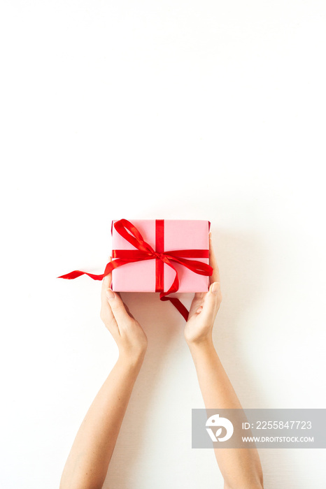 Womens hands hold pink gift box on white background. Flatlay, top view Valentines Day holiday conc