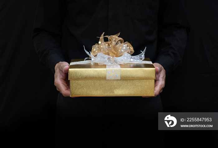 Man in black holding gold gift box