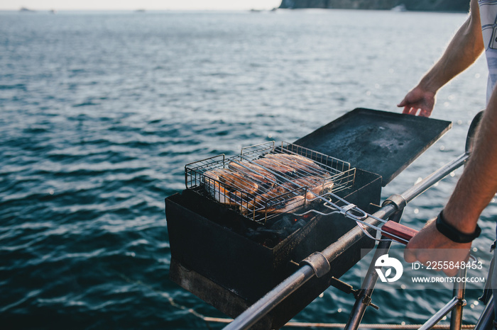 Man grilling fish on yacht with beautiful sea view