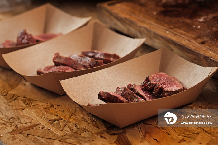 Delicious beef slices in craft paper container on street food festival