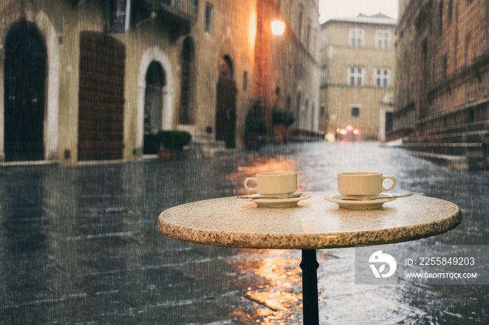 Rainy day in old European city, wet cafe table with two cups of coffee