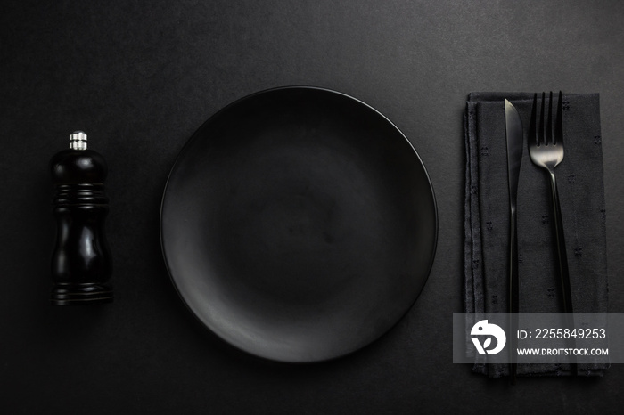 Elegant black table setting: plates, napkin and silverware over black background. Flat lay. copy spa