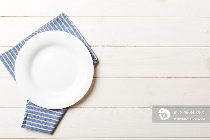 Top view on colored background empty round white plate on tablecloth for food. Empty dish on napkin 