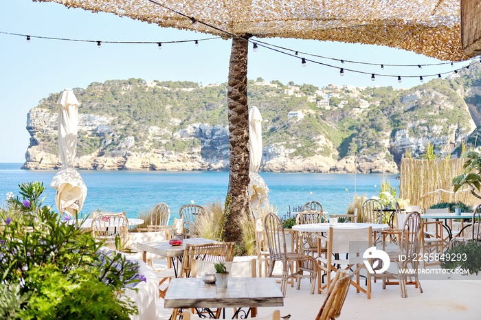 Beach restaurant under a canopy located empty wooden tables and chairs