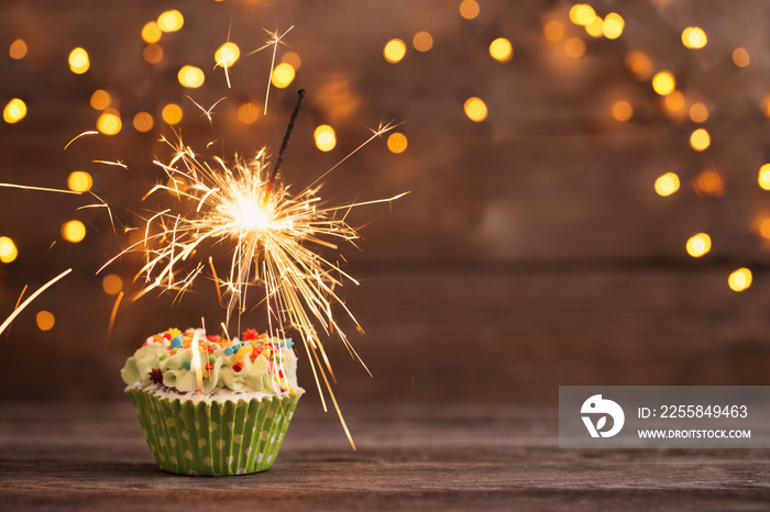 cupcake with sparkler on old wooden background
