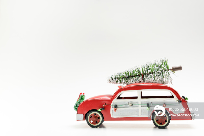 Miniature red vintage car carrying a Christmas tree on top for Xmas theme