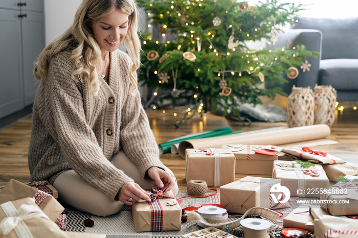 Caucasian woman wrapping Christmas gifts on the floor