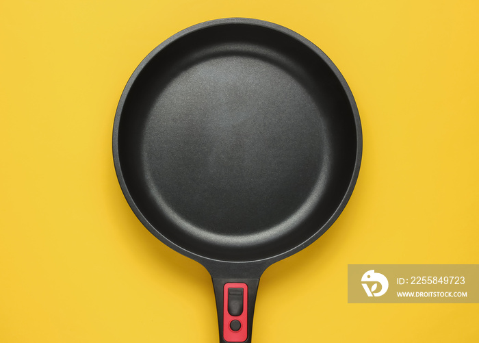 Frying pan with a non-stick coating on yellow background. Cooking minimalism concept. Top view