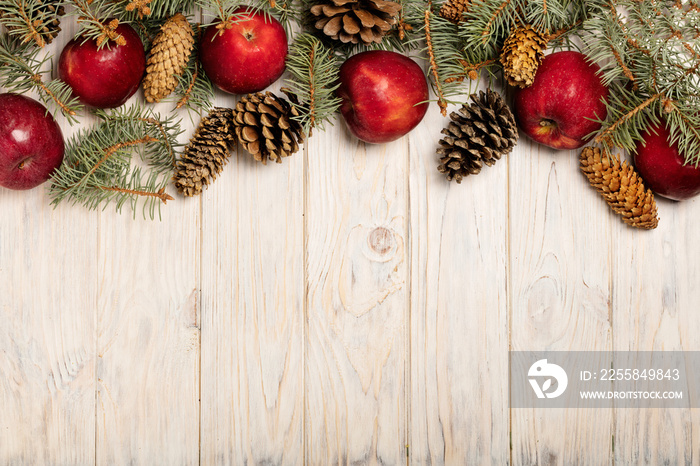 Christmas apples and spruce branches with cones on white wooden